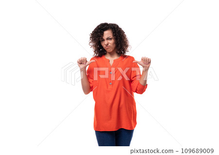 young caucasian business woman with a curly hairstyle dressed in an orange shirt makes a grimace 109689009