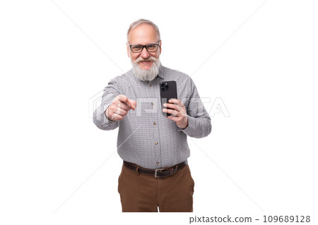grandfather with a white beard and mustache is dressed in a shirt and trousers is mastering new 109689128