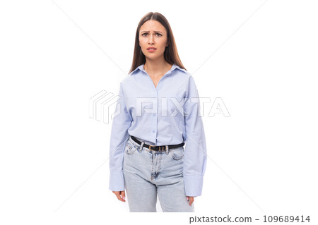 young caucasian model woman with dark straight hair dressed in a blue blouse looks upset at the young caucasian model woman with dark straight hair dressed in a blue blouse looks upset at the 109689414