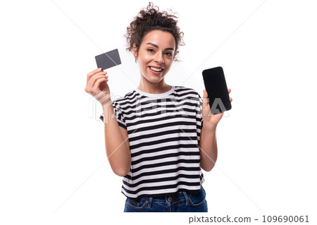 young caucasian woman with curly hair dressed in a striped summer t-shirt holds a plastic card with 109690061