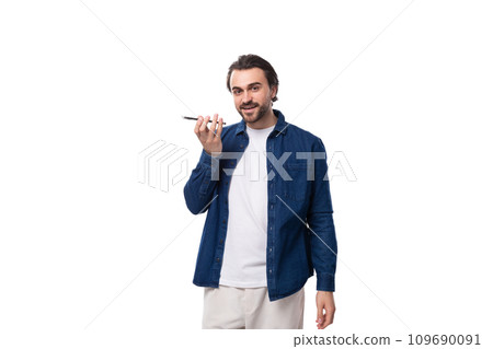 young brutal caucasian man with black hair dressed in a blue shirt records a voice message on the young brutal caucasian man with black hair dressed in a blue shirt records a voice message on the 109690091