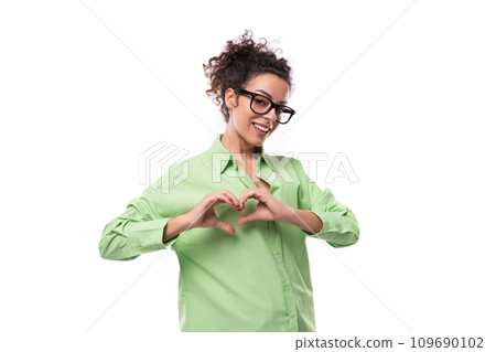 pretty young brunette curly woman in glasses is dressed in a green shirt on a white background with pretty young brunette curly woman in glasses is dressed in a green shirt on a white background with 109690102
