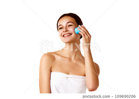 Shower routine. Smiling tender young girl cleansing face with washing brush against white background 109690206