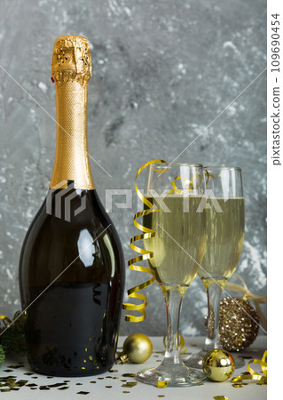 Champagne bottle with confetti, glasses and christmas decor on colored holiday background. Flat lay New Year decorations 109690454