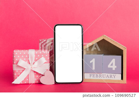 mobile phone with blank screen on colored background with hearts, calendar and gift box, valentine day 14 february concept perspertive view flat lay 109690527