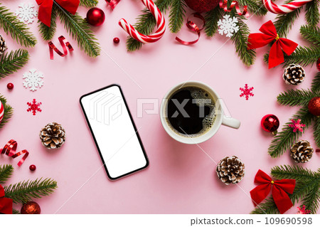 top view of smart phone with hot cup of coffee. Christmas decoration on colored background top view of smart phone with hot cup of coffee. Christmas decoration on colored background 109690598
