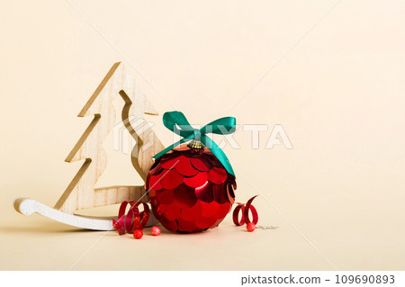 Christmas ball with decorative wooden tree on colored background. decoration bauble with ribbon bow with copy space 109690893