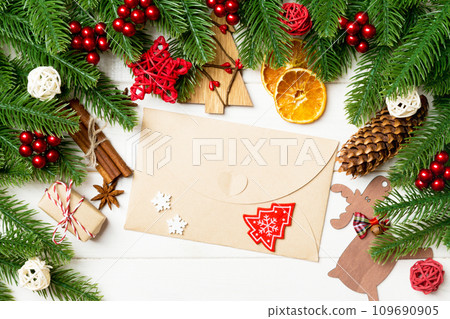 Top view of fir tree branches, envelope and festive decorative toys on wooden background. New Year time concept Top view of fir tree branches, envelope and festive decorative toys on wooden background. New Year time concept 109690905
