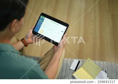 Over shoulder view of senior man transferring money or paying bills on digital tablet 109691317
