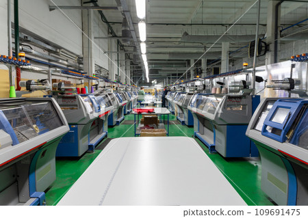 A row of industrial textil flat knitting machines in a knitwear factory. A row of industrial textil flat knitting machines in a knitwear factory. 109691475