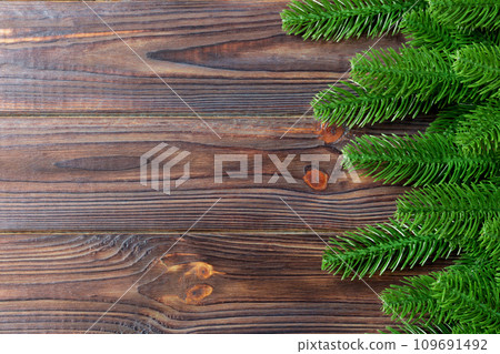 Top view of frame made of fir tree branches on wooden background. Christmas concept with empty space for your design Top view of frame made of fir tree branches on wooden background. Christmas concept with empty space for your design 109691492