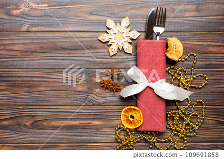 Top view of utensils on festive napkin on wooden background. Christmas decorations with dried fruits and cinnamon. New year dinner concept with copy space 109691858