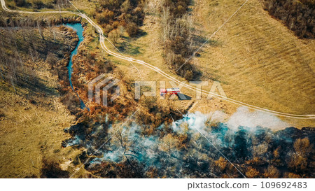 Aerial View. Spring Dry Grass Burns During Drought Hot Weather. Bush Fire And Smoke. Fire Engine, Fire Truck On Firefighting Operation. Wild Open Fire Destroys Grass. Ecological Problem Air Pollution 109692483