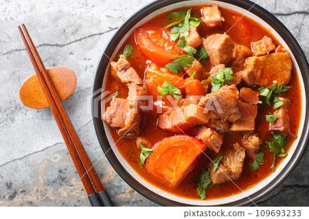 Spicy Pork Belly cooked with tomatoes, onions, sweet soy sauce and spices close-up in a bowl. Horizontal top view Spicy Pork Belly cooked with tomatoes, onions, sweet soy sauce and spices close-up in a bowl. Horizontal top view 109693233
