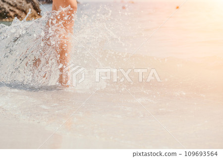 Sea beach travel - woman walking on sand beach leaving footprints in the white sand. Female legs walking along the seaside barefoot, close-up of the tanned legs of a girl coming out of the water. Sea beach travel - woman walking on sand beach leaving footprints in the white sand. Female legs walking along the seaside barefoot, close-up of the tanned legs of a girl coming out of the water. 109693564