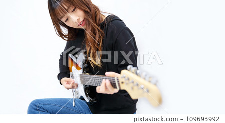 Image of a woman playing an electric guitar 109693992