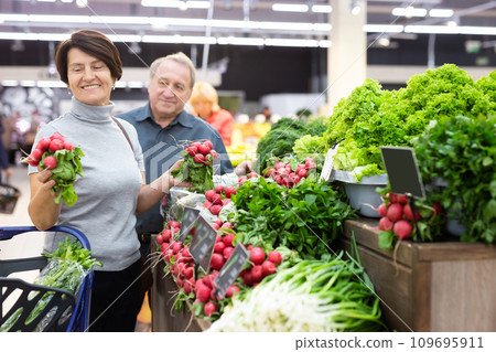 Smiling happy couple is choosing bell peppers and other vegetables in supermarket Smiling happy couple is choosing bell peppers and other vegetables in supermarket 109695911