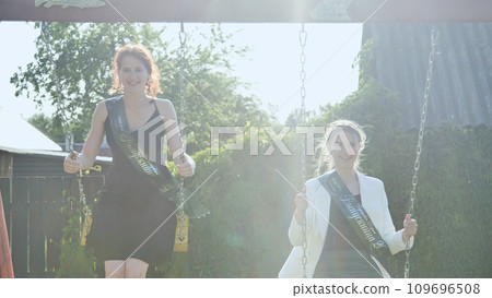 Girls graduating from college ride the swings. Girls graduating from college ride the swings. 109696508