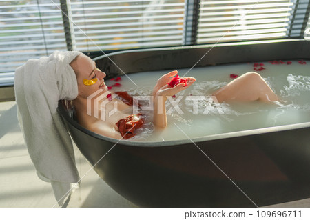 Spa relaxation. Woman lying in bath with holding glass with red wine. Girl relaxing in bathroom at home. Pretty female taking hot bath drinking wine. Stress relief. Rest after hard working day 109696711