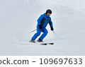 A man in blue sportswear on skis rides down a snowy slope 109697633
