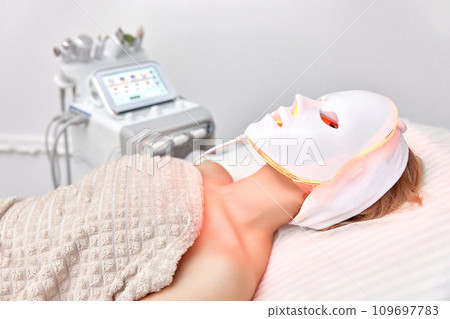 Woman lies with led light therapy facial mask in beauty salon 109697783