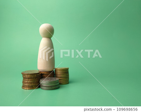 Wooden people figures and coins on a green background with copy space. Wooden people figures and coins on a green background with copy space. 109698656