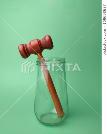Wooden gavel on glass jar on a green background with copy space. 109698657