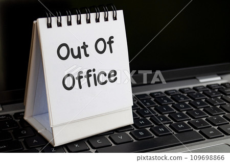 Out of office text on notepad with laptop background. Out of office concept Out of office text on notepad with laptop background. Out of office concept 109698866