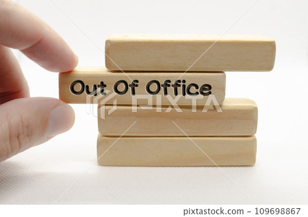Hand pulling out wooden block with out of office text on white background Hand pulling out wooden block with out of office text on white background 109698867