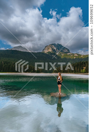 Woman Solo Traveler Standing in Black Lake 109699652