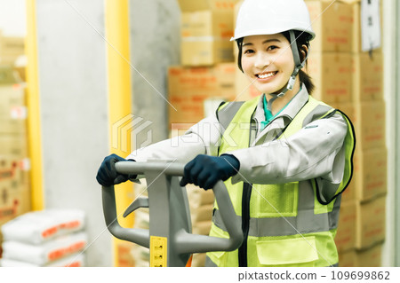 Smiling female worker moving inventory with a jack Smiling female worker moving inventory with a jack 109699862