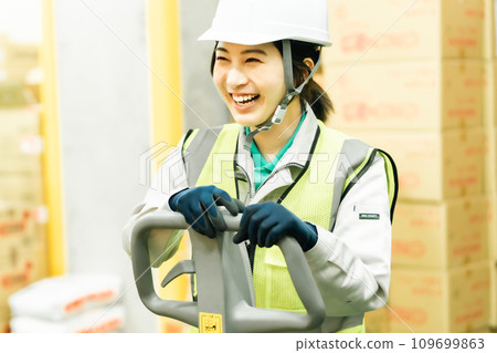 Smiling female worker moving inventory with a jack 109699863