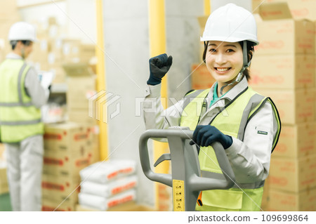 A female worker pumping her fists while moving inventory using a jack A female worker pumping her fists while moving inventory using a jack 109699864