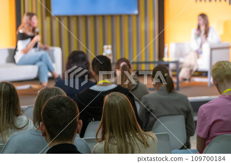 Back view of businesspeople listening to female speakers on stage during global presentation on conference hall Back view of businesspeople listening to female speakers on stage during global presentation on conference hall 109700184