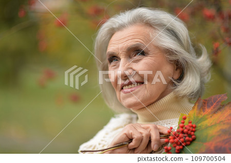 Happy senior woman in the autumn park 109700504