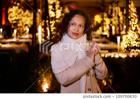Attractive woman with hands cupped, making cherished wish for Christmas, standing on the street with beautiful lightings Attractive woman with hands cupped, making cherished wish for Christmas, standing on the street with beautiful lightings 109700650