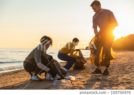 Earth day. Volunteers activists team collects garbage cleaning of beach coastal zone. Woman mans puts plastic trash in garbage bag on ocean shore. Environmental conservation coastal zone cleaning Earth day. Volunteers activists team collects garbage cleaning of beach coastal zone. Woman mans puts plastic trash in garbage bag on ocean shore. Environmental conservation coastal zone cleaning 109700976