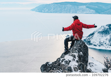 Tourist sitting on Chersky stone and looking to beautiful view of lake Baikal and Angara river flowing in Listvyanka a small resort township on the bank of Lake Baikal, Russia. 109702276