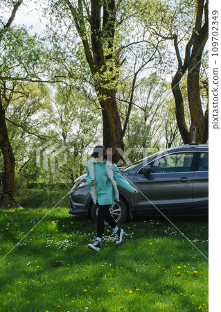 a woman runs from a parked car on a green lawn in nature a woman runs from a parked car on a green lawn in nature 109702349