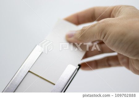 Hand taking out a business card from the business card holder Hand taking out a business card from the business card holder 109702888