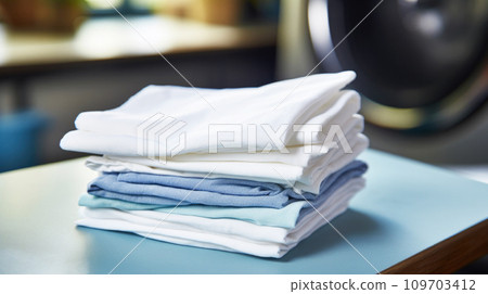 Stack of neatly folded shirts in white and blue color, freshly washed and ironed in modern home with natural light, sense of order and domestic tranquility. Spring cleaning and organization 109703412