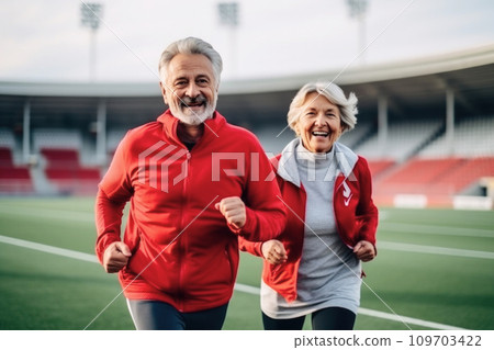 Elderly smiling couple, full of vitality and joy, joging on tracks of stadium. Senior Health and Fitness. Embracing healthy habits in retirement. Joy of sport in golden years 109703422
