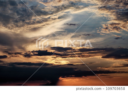 The sun shining through scattered clouds at sunset. The sun shining through scattered clouds at sunset. 109703658