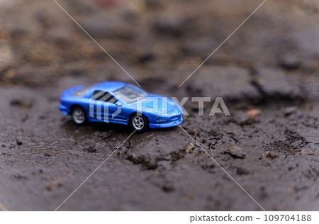 A blue car drives along a road destroyed by a landslide. A blue car drives along a road destroyed by a landslide. 109704188