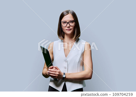 Young confident woman with laptop computer in hands on gray background 109704259