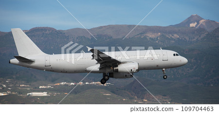 The plane lands.Airplane, passengers flying in the sky, preparing to land at the airport. El Teide volcano in the background The plane lands.Airplane, passengers flying in the sky, preparing to land at the airport. El Teide volcano in the background 109704463