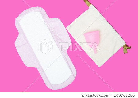 menstrual cup and regular feminine pad on a pink background, top view, copy space. Zero waste concept. Eco-friendly menstrual products 109705290