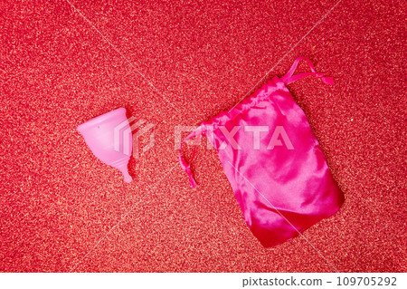 menstrual cup with satin pouch on shiny red background, top view. Zero waste concept. Eco-friendly menstrual products menstrual cup with satin pouch on shiny red background, top view. Zero waste concept. Eco-friendly menstrual products 109705292