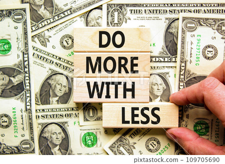 Do more with less symbol. Concept word Do more with less on beautiful block. Dollar bills. Beautiful background from dollar bills. Businessman hand. Business do more with less concept. Copy space. 109705690