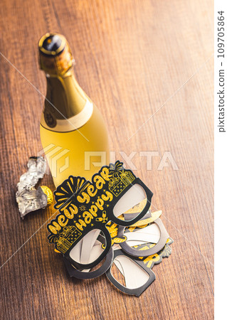 Happy new year background. Black funny paper glasses and bottle of champagne on wooden table. Happy new year background. Black funny paper glasses and bottle of champagne on wooden table. 109705864